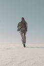 Man in Gray Coat and Pants Standing on White Sand