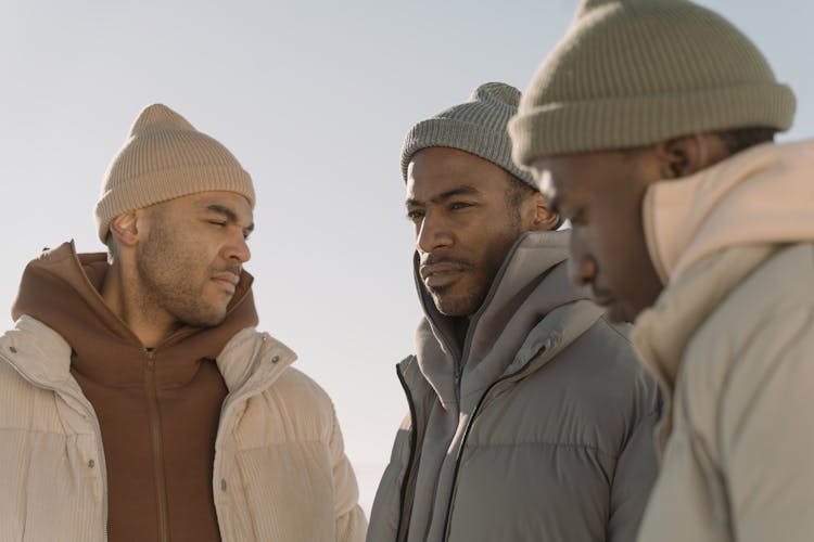 Three Men Wearing Knit Hats And Hoodie With Puffer Jackets