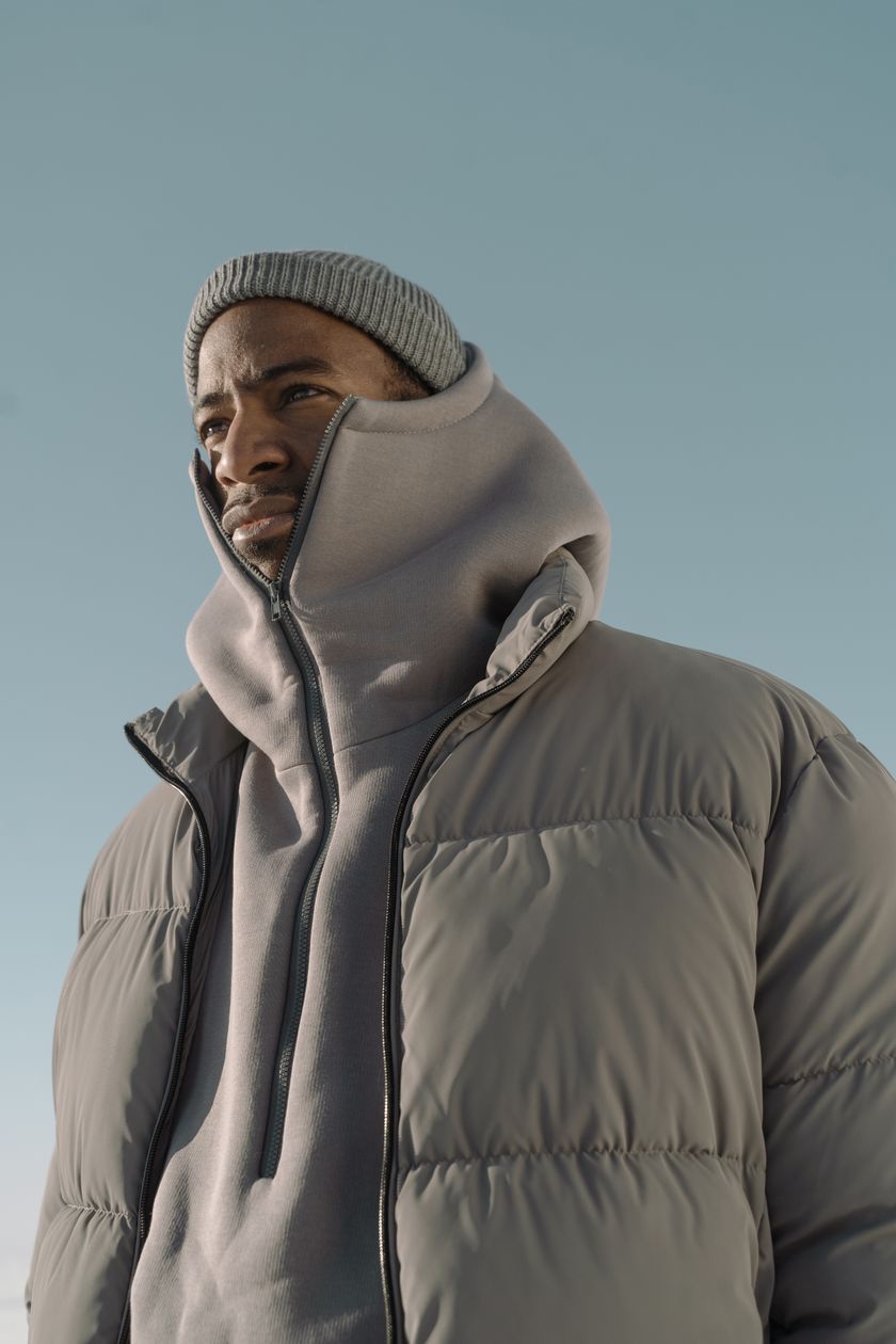 A padded puffer jacket worn outdoors, the horizontal quilted baffles across chest and shoulder in frame
