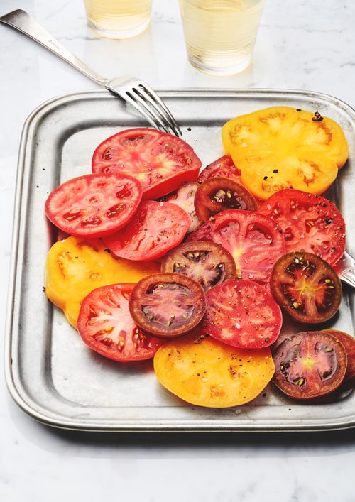 Free Vibrant slices of heirloom tomatoes arranged on a tray, ready to enjoy. Stock Photo