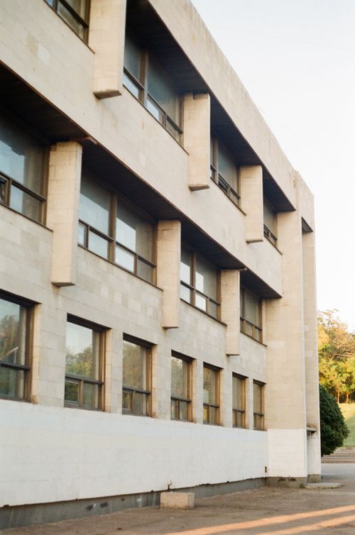 Free Exterior view of a modern concrete building featuring glass windows and clean architectural lines. Stock Photo