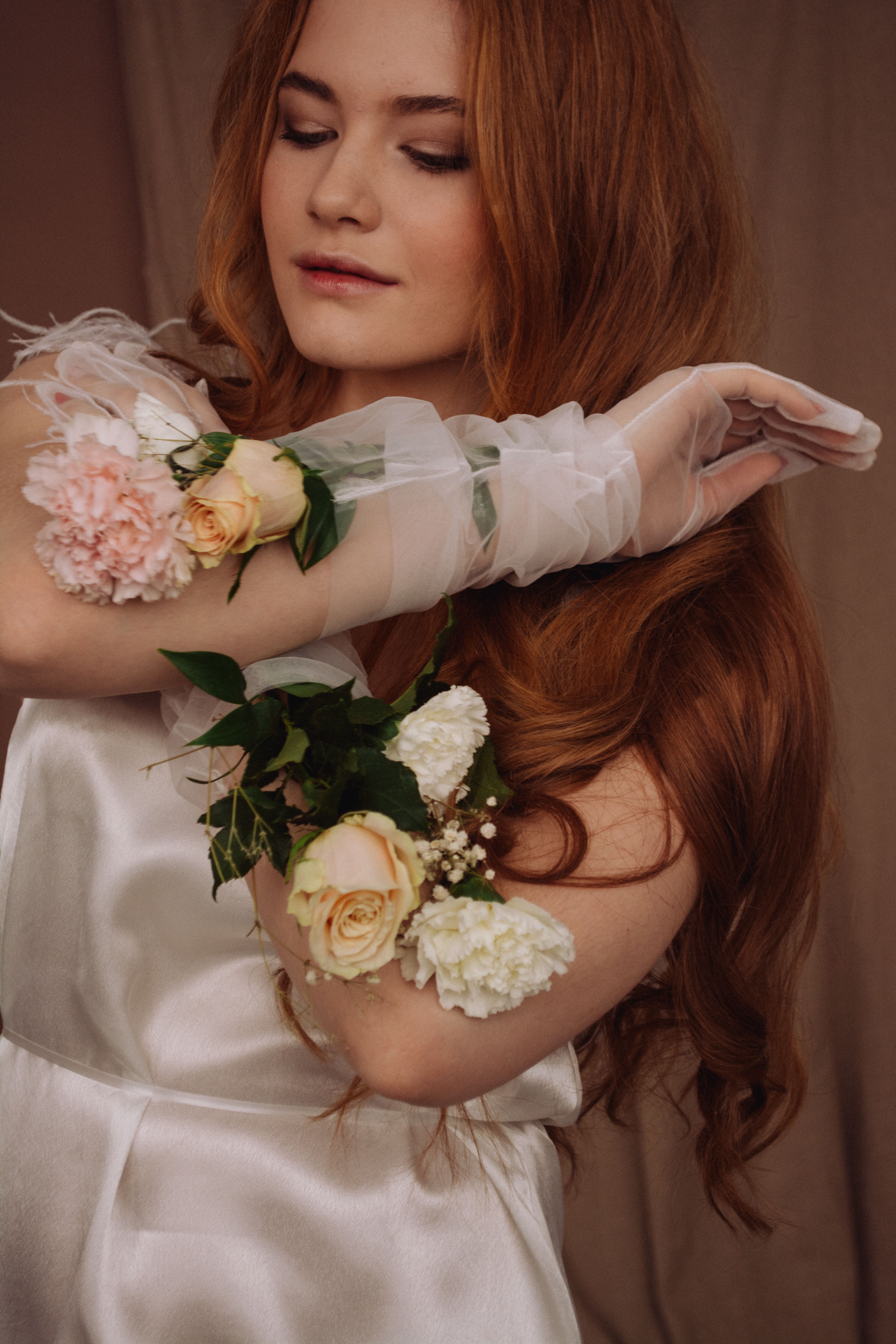 A beautiful bride posing elegantly indoors with a floral bouquet and white gown