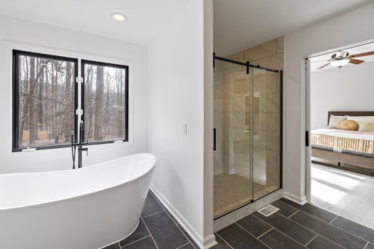 Sleek bathroom featuring a freestanding tub, glass shower, and a view of the forest.