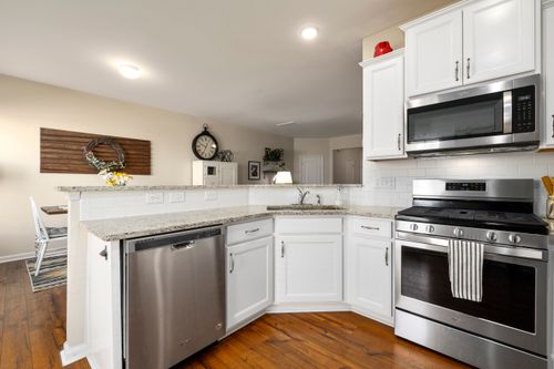 Free Bright kitchen featuring modern appliances and white cabinetry with hardwood floor. Stock Photo