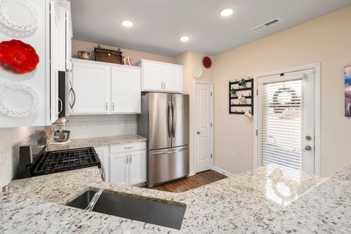 Free Stylish modern kitchen featuring white cabinets, granite countertops, and stainless steel appliances. Stock Photo