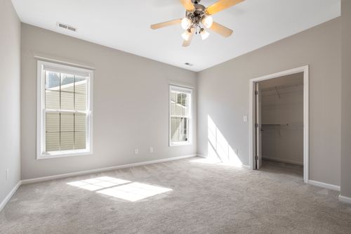 Free Sunlit empty room with beige carpet and ceiling fan, ideal for real estate listings. Stock Photo