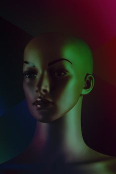 Mannequin head with vivid lighting, casting shadows for a dramatic still life effect.