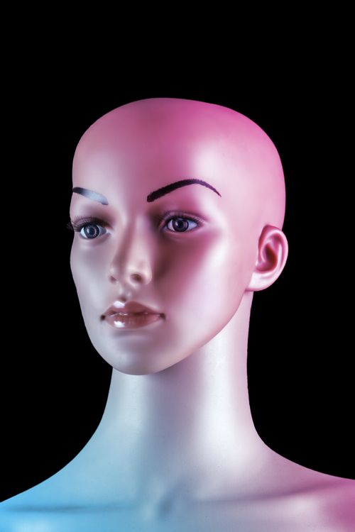 Free Close-up studio shot of a mannequin head with pink and blue lighting on a black background. Stock Photo