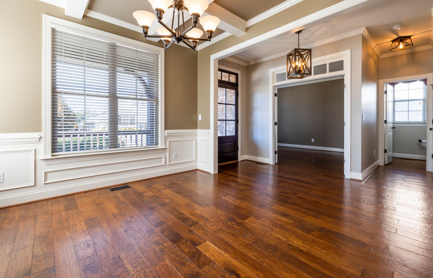 Elegant room with wooden flooring, chandelier, and natural lighting.