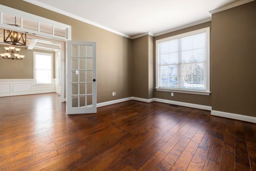 Free Bright and empty room with hardwood flooring, large windows, and elegant lighting. Stock Photo
