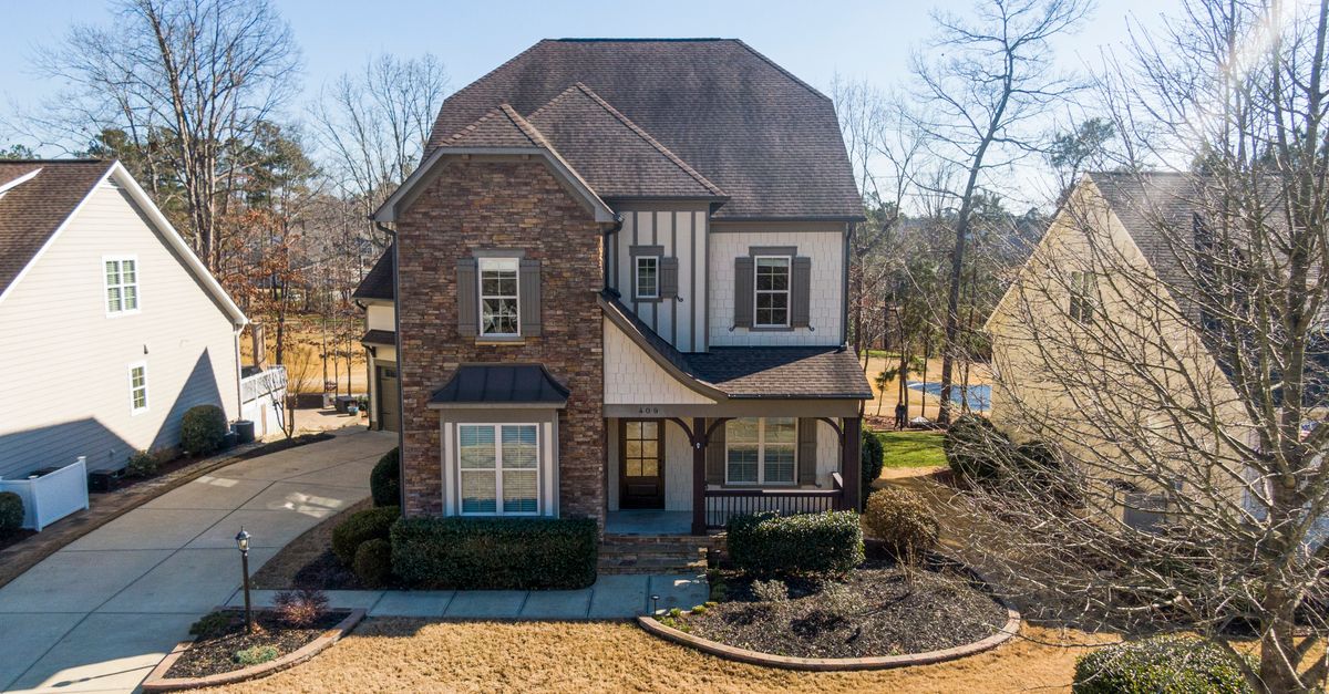 A beautiful two-story house with stone facade and lush yard in Holly Springs, NC.