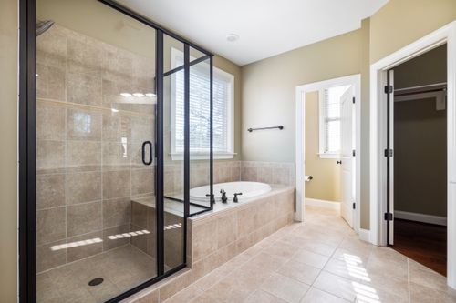 Free Spacious and bright bathroom featuring glass shower and built-in bathtub with natural light. Stock Photo