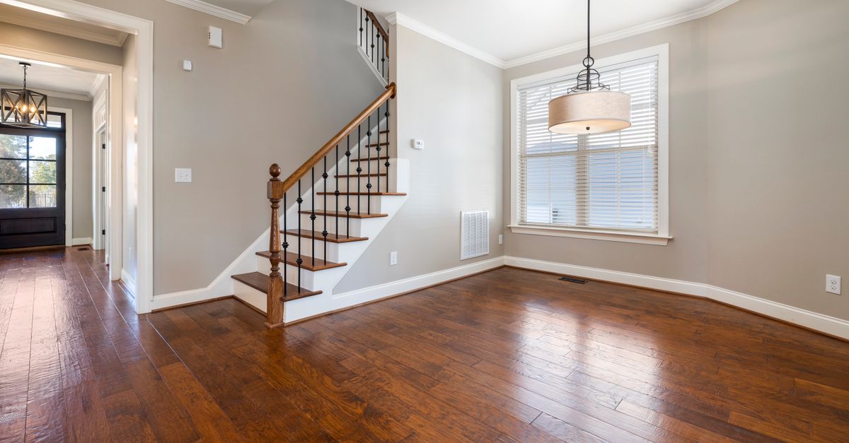 Bright and airy room with wooden floors and staircase, ideal for modern living.