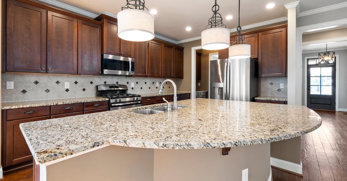 Spacious kitchen featuring a granite island, dark wood cabinets, and stainless steel appliances.