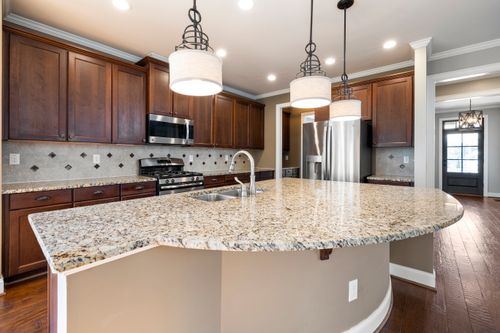 Free Spacious kitchen featuring a granite island, dark wood cabinets, and stainless steel appliances. Stock Photo