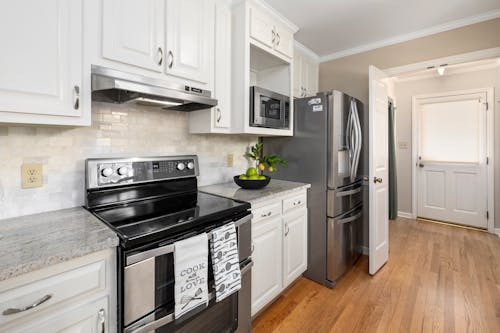 Free A White Themed Kitchen with Stainless Steel Appliances Stock Photo
