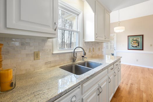 Spacious white kitchen interior with granite countertops and natural light.