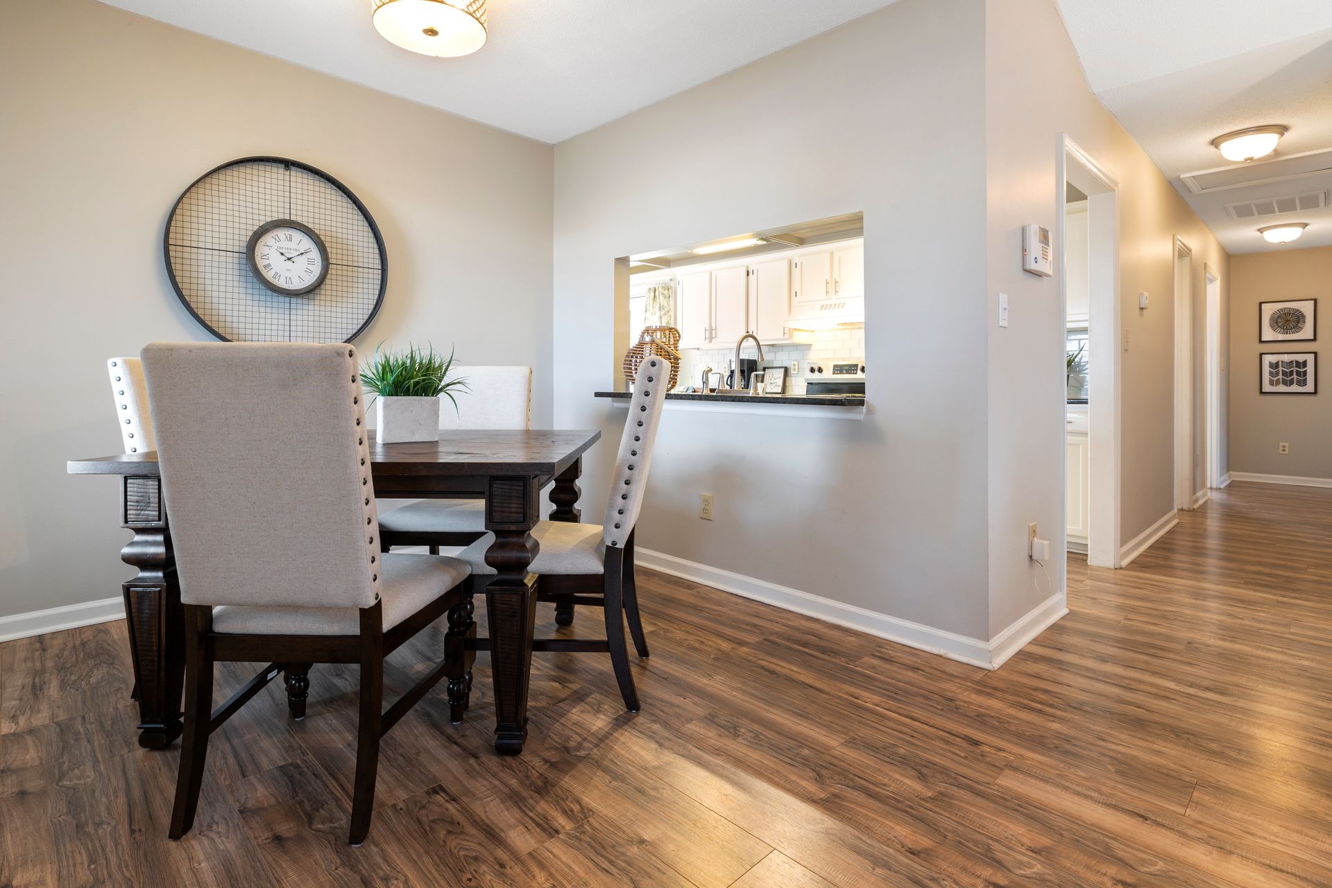 Elegant dining room with wooden table, modern chairs, and wall clock for home interior design.