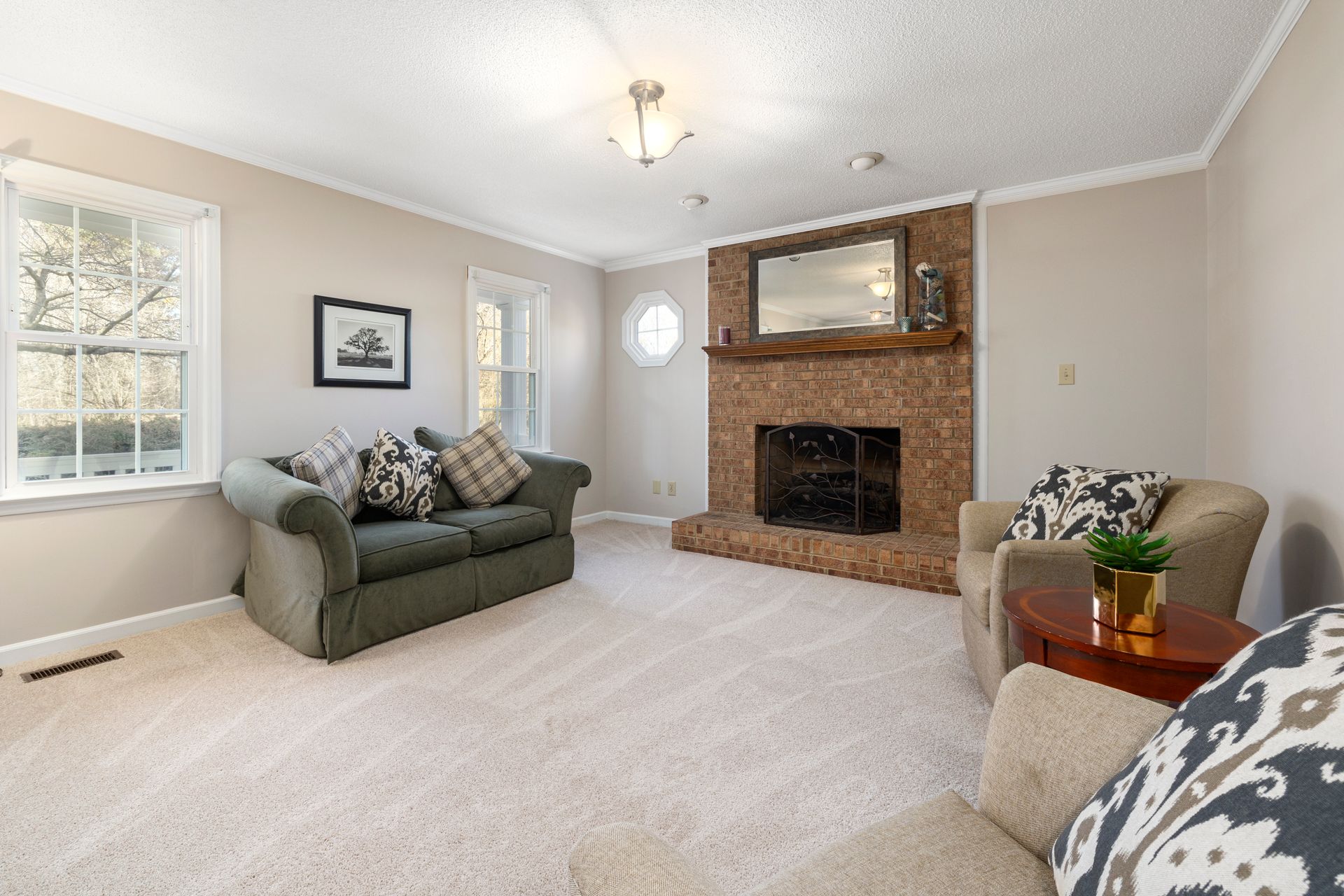 Bright and elegant living room featuring a classic brick fireplace and comfortable seating.