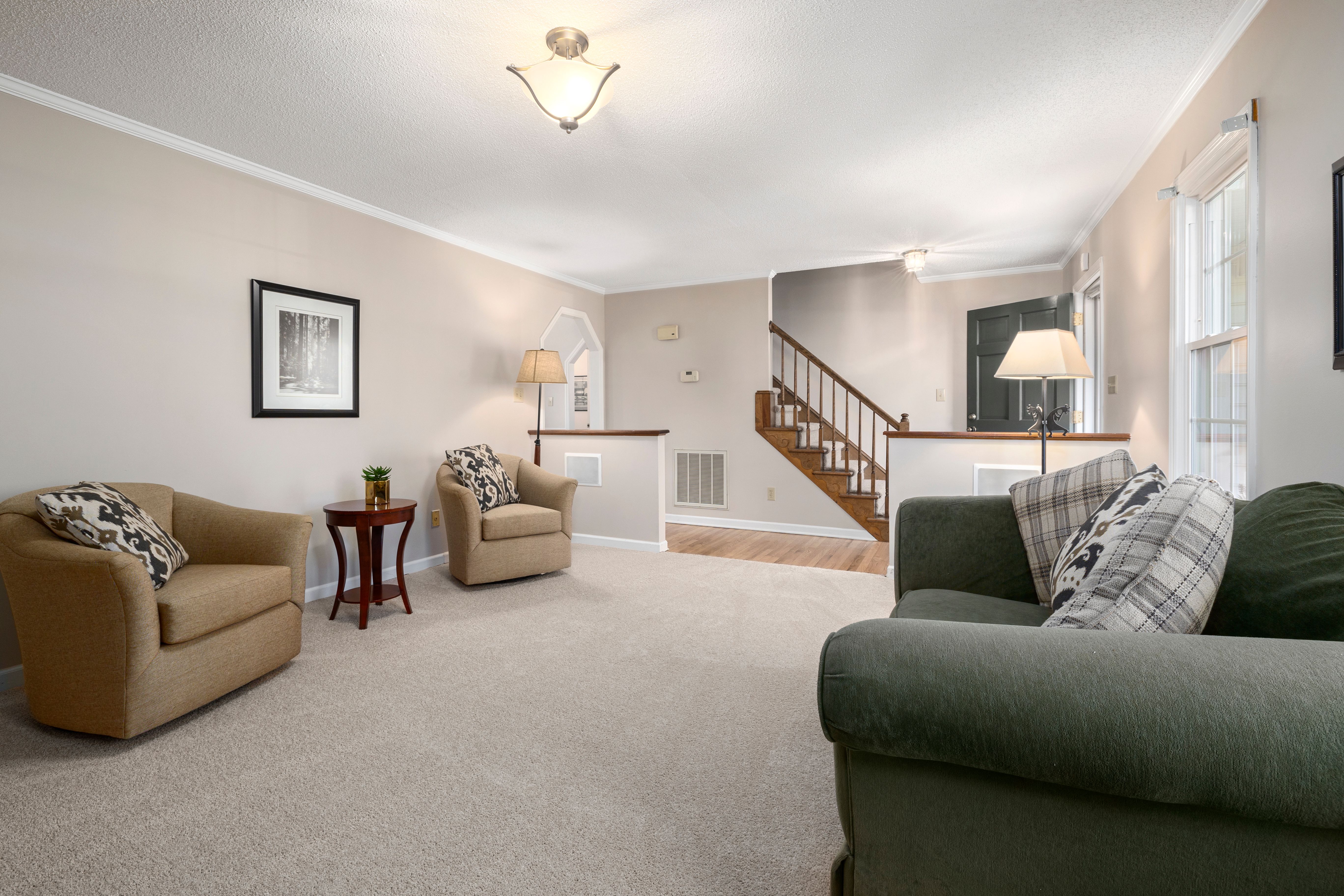 Spacious living room with contemporary furniture, neutral tones, and natural lighting.