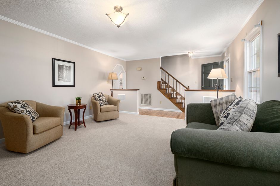 Spacious living room with contemporary furniture, neutral tones, and natural lighting.