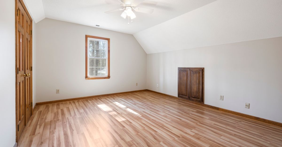Bright empty room with hardwood floor and ceiling fan, perfect for real estate listings.