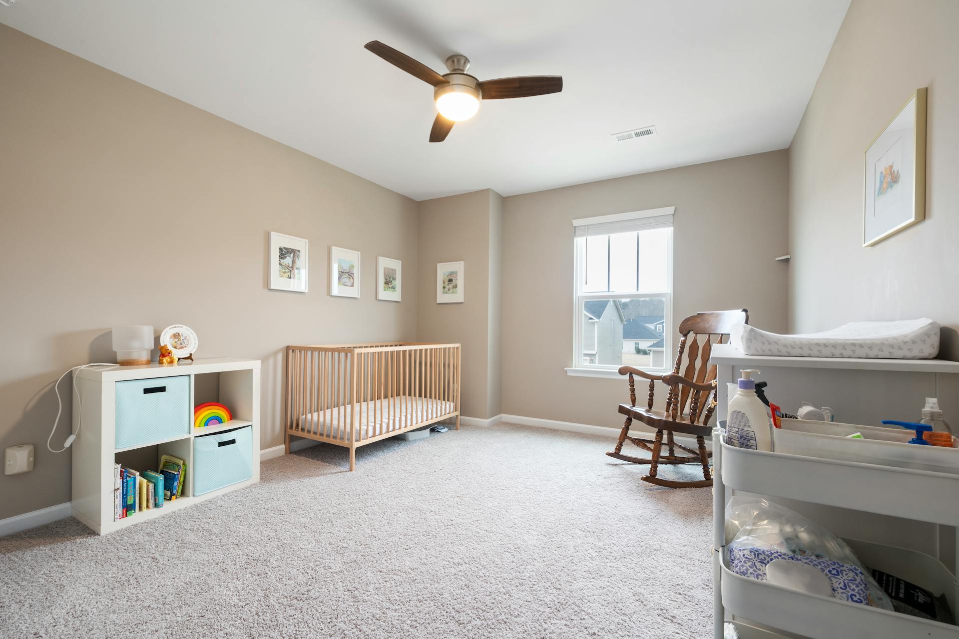 Bright, minimalist children's room with a crib, rocking chair, and organized storage unit.