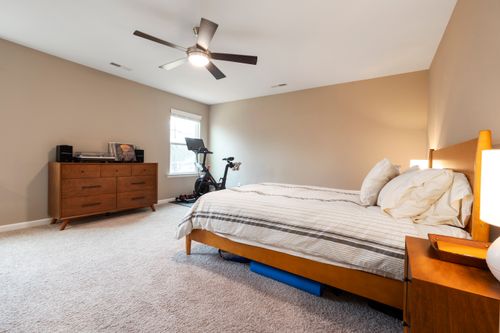 Free Spacious modern bedroom featuring an exercise bike and stylish wooden furniture. Stock Photo