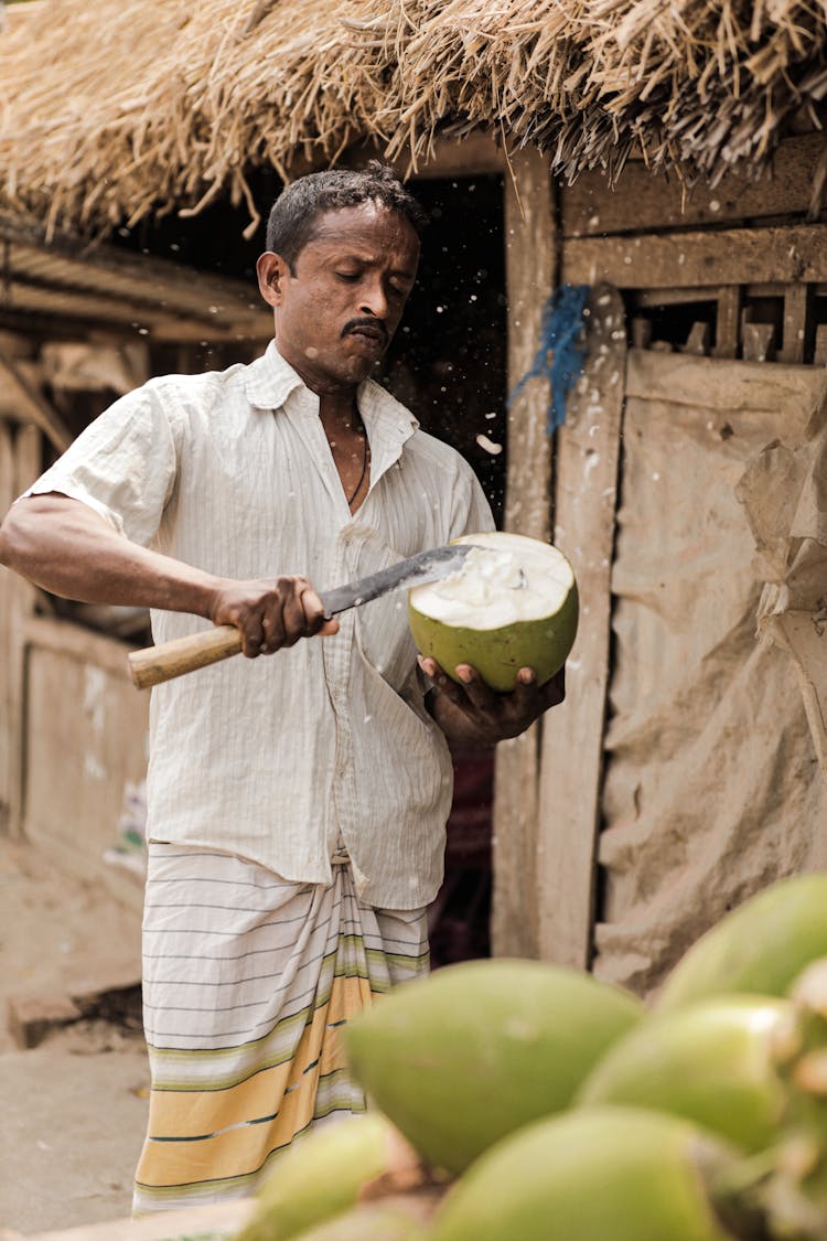 Indian Man Cutting Coconut In Village