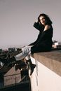 Woman in Black Dress Sitting on Concrete Wall