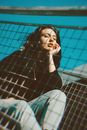 Woman in Black Long Sleeve Shirt and Blue Denim Jeans Sitting on Chair