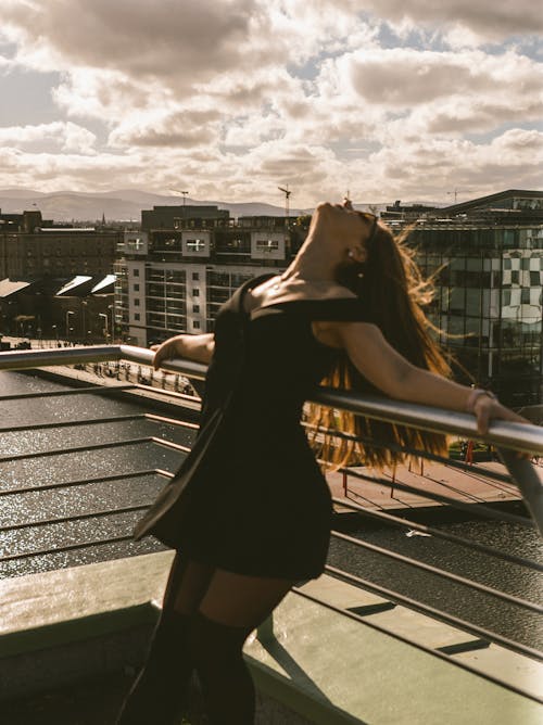 Free Woman in a Black Dress Leaning on Railings Stock Photo