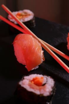 Appetizing sushi rolls and nigiri garnished with chopsticks, showcasing Japanese cuisine.