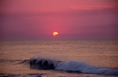 Free A breathtaking sunset over the ocean with dramatic waves under a vivid pink sky. Stock Photo