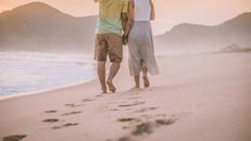 Man in Green Tank Top and White Shorts Standing on Beach