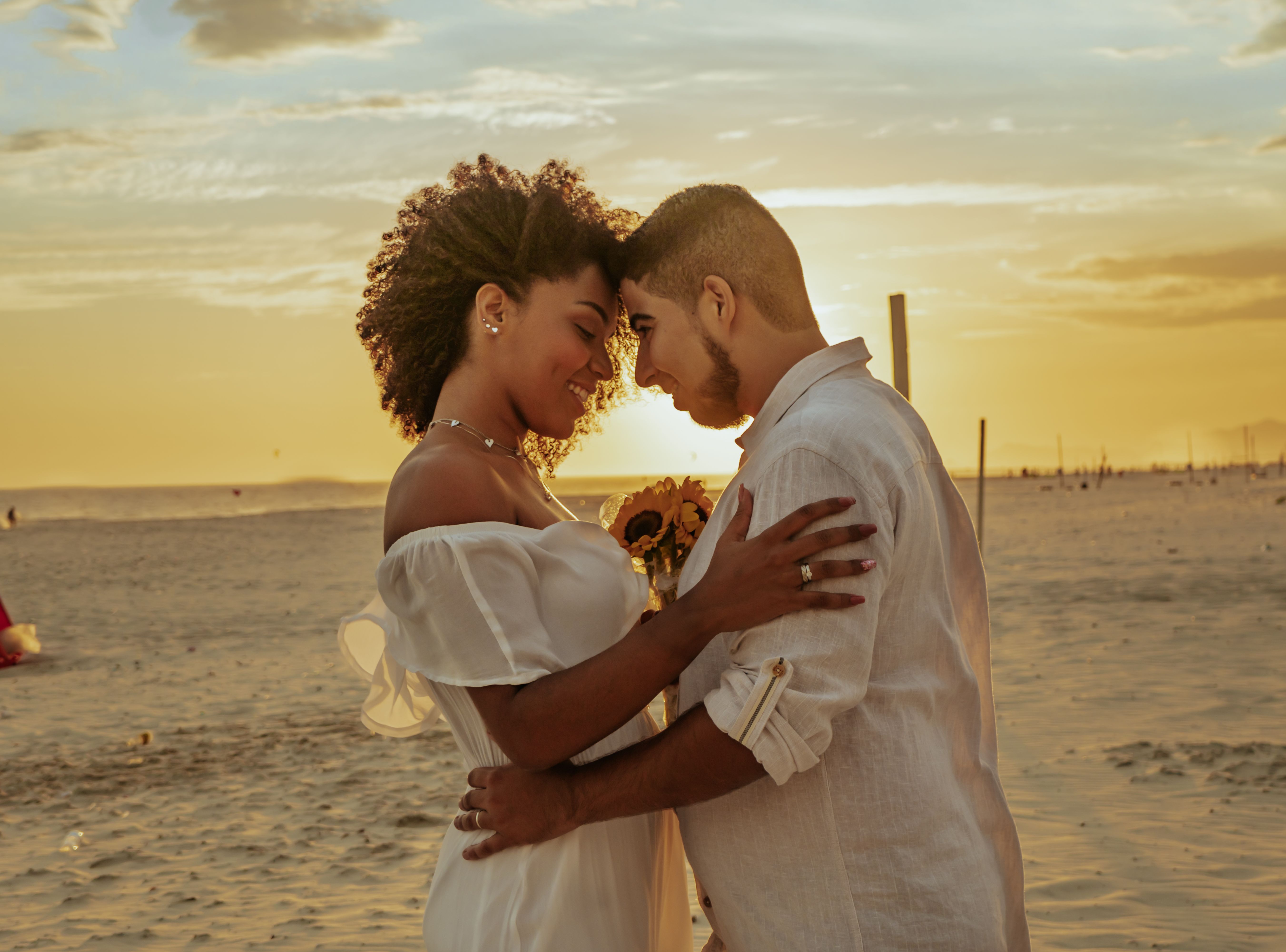 A loving couple embracing on a sandy beach at sunset, capturing affection and warmth.