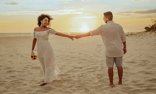 A Couple Standing on the Beach Sand while Holding Hands
