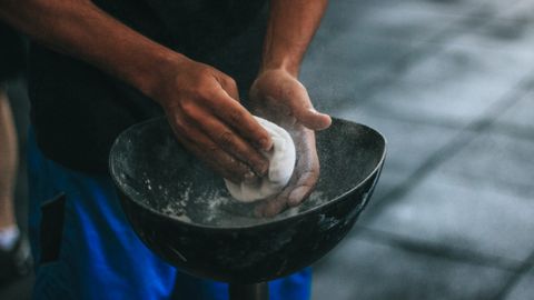 A man prepares chalk powder for climbing exercises with focus on hands in motion.