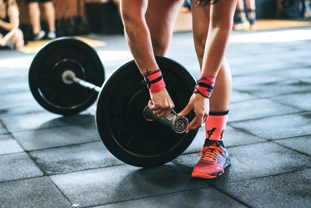 Athlete gripping a loaded barbell on a gym floor