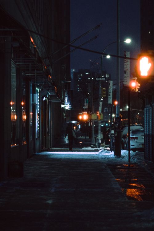 Free Sidewalk between glowing traffic lights and residential buildings located on snowy street in city with streetlamp at cold winter night Stock Photo