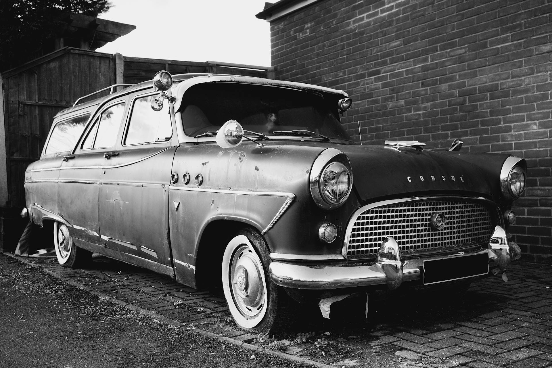 Monochrome image of a vintage car parked outdoors, showcasing classic design.