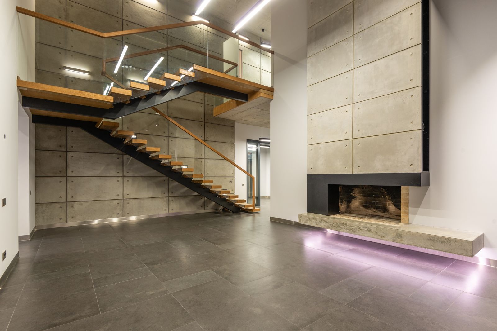 Modern minimalist home interior with a floating staircase, stone floor and warm lighting