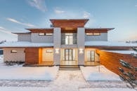 Backyard view of new modern luxurious cottage house with stone and wooden facade and illumination in winter countryside