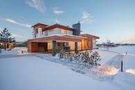 Exterior view of luxurious residential house with roofed parking and spacious backyard in snowy winter countryside