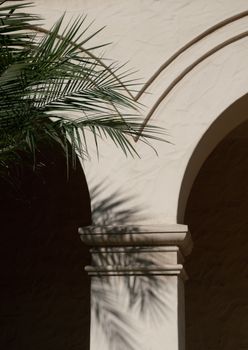Elegant stone archway with palm leaf shadows creating a serene architectural scene.