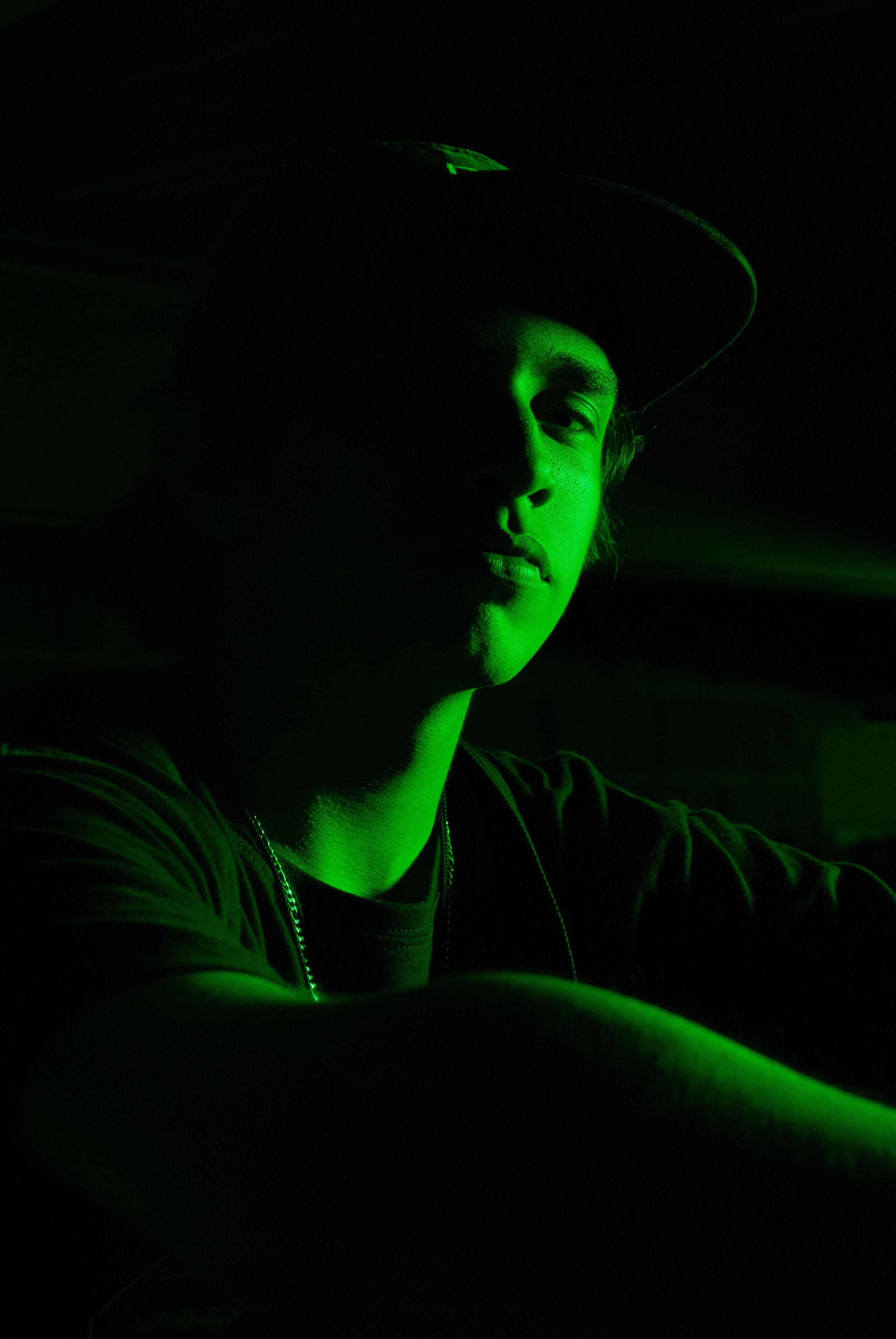 Free Dark, moody portrait of a young man with dramatic green lighting, creating a cinematic feel. Stock Photo