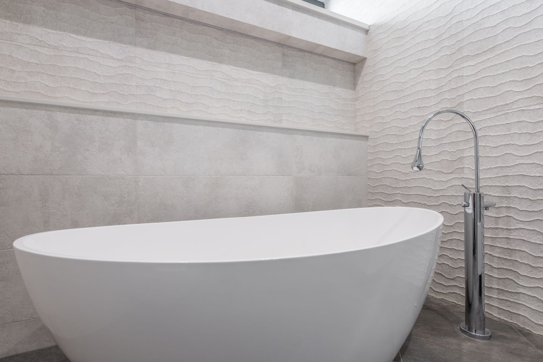 Freestanding bath surrounded by softly textured neutral contemporary walls