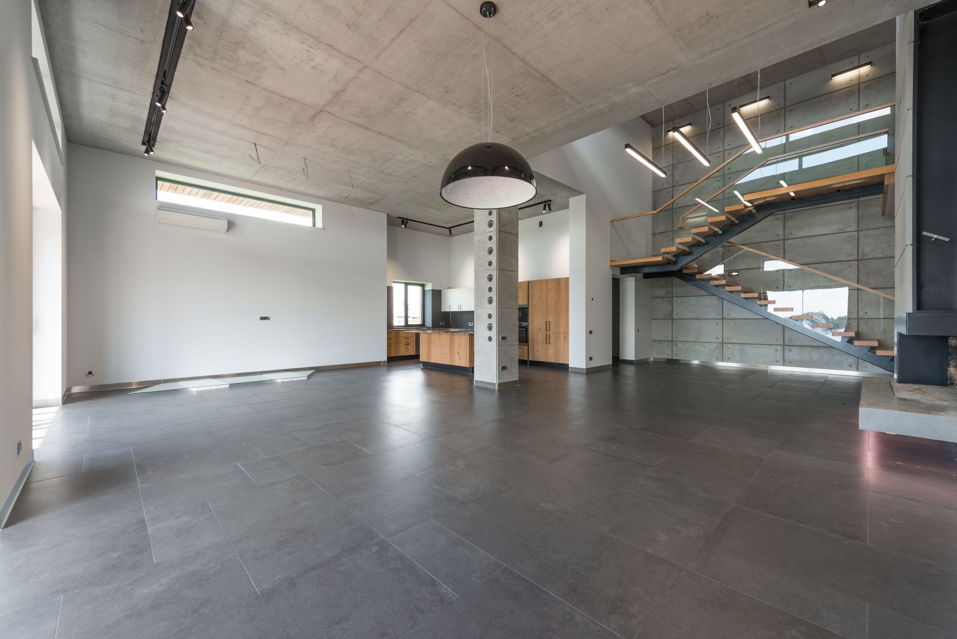 Modern loft style home interior design of spacious hallway with gray stone floor and stairway in contemporary minimalist luxury house