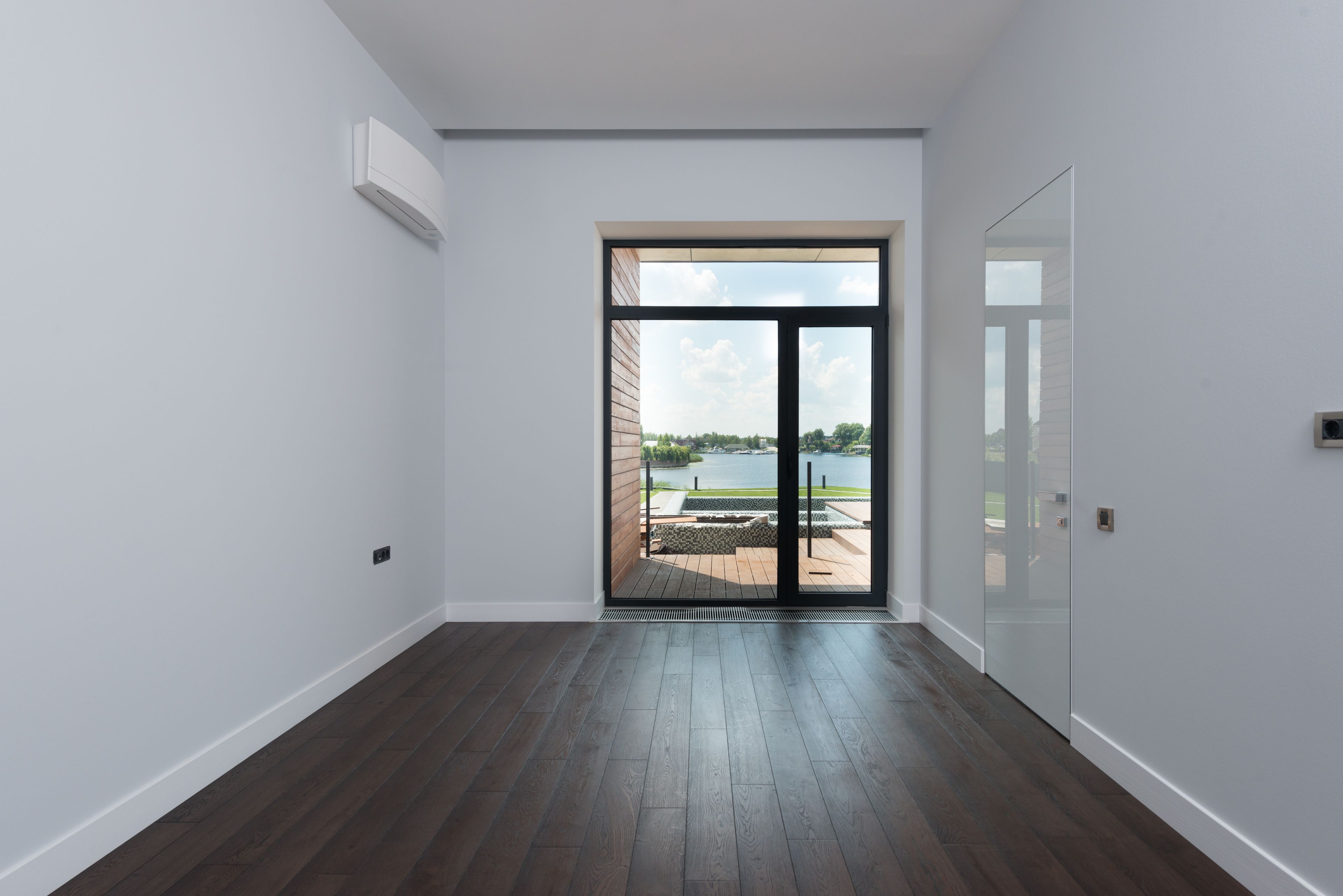 Couloir d'appartement entièrement dégagé, mur blanc et grande fenêtre en fond.