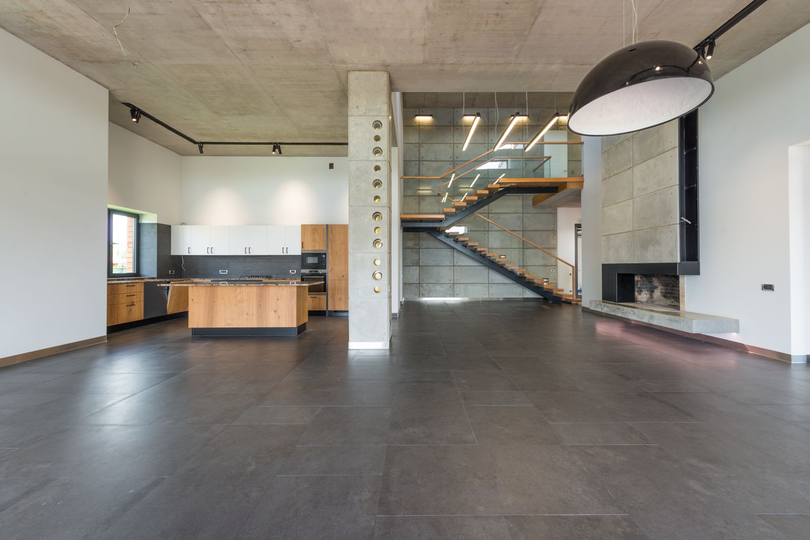 Minimalist luxury home interior with a spacious hallway, stone floor and open-plan kitchen